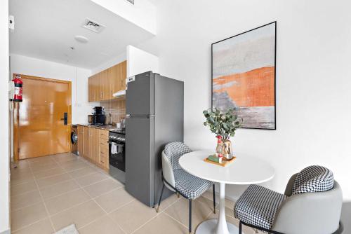 a kitchen with a white table and a refrigerator at Silkhaus Vacation Homes New studio in Silicon Oasis ASB Tower in Dubai