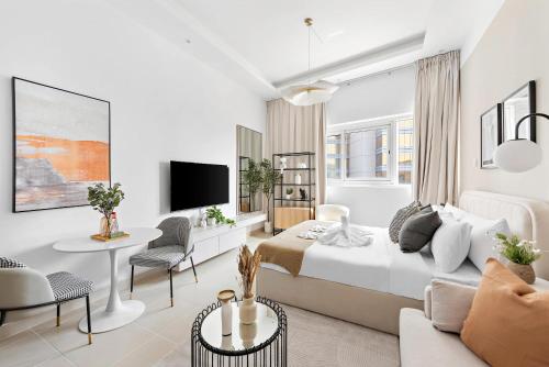 a white bedroom with a bed and a living room at Silkhaus Vacation Homes New studio in Silicon Oasis ASB Tower in Dubai