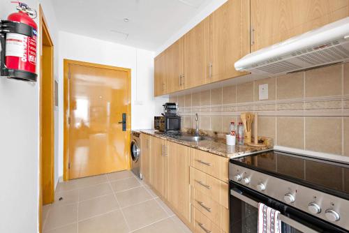 a kitchen with wooden cabinets and a stove top oven at Silkhaus Vacation Homes New studio in Silicon Oasis ASB Tower in Dubai