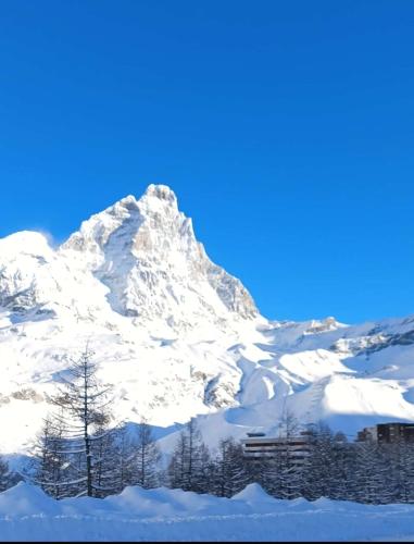 a snow covered mountain with a building in front of it at Casa Elvezia in Breuil-Cervinia