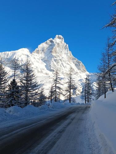 a road with a snow covered mountain in the background at Casa Elvezia in Breuil-Cervinia