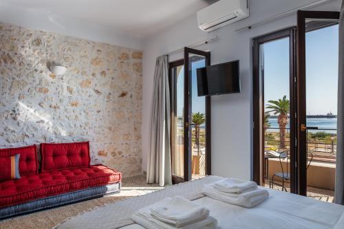 a bedroom with a red couch and a tv at Chryssi 01, Stylish Seaside Spot in the Heart of Rethymno in Rethymno Town