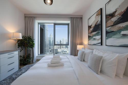 a bedroom with a large white bed with a large window at Signature 2BR with Burj Khalifa & Fountain View in Dubai