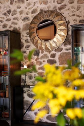 a stone wall with a mirror and yellow flowers at De Aldaca Rural - Only Adults in Jerte