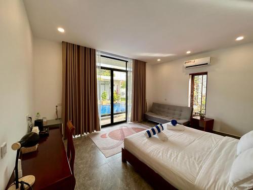 a bedroom with a bed and a couch and a window at Enchanted Pool Bungalows Siem Reap, right near the Wake Park in Phumĭ Kruŏs