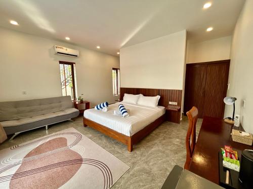 a bedroom with a bed and a couch at Enchanted Pool Bungalows Siem Reap, right near the Wake Park in Phumĭ Kruŏs