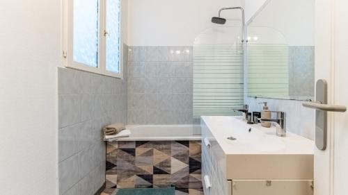 La salle de bains est pourvue d'un lavabo blanc et d'une baignoire. dans l'établissement Les Toits de Darcy - Dijon Centre historique, à Dijon