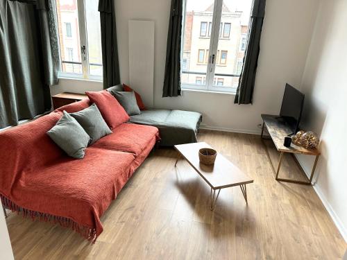 Una sala de estar con un sofá rojo y una mesa. en BO'M Appart, en Tourcoing