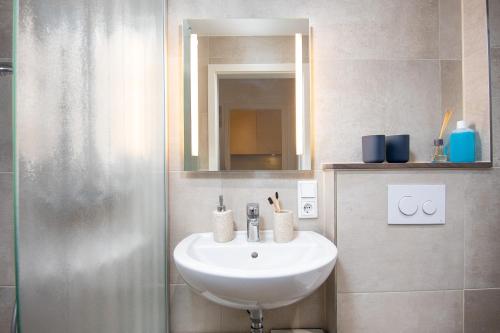 ein Badezimmer mit Waschbecken, Spiegel und Dusche in der Unterkunft Huus Gerda in Krummhörn