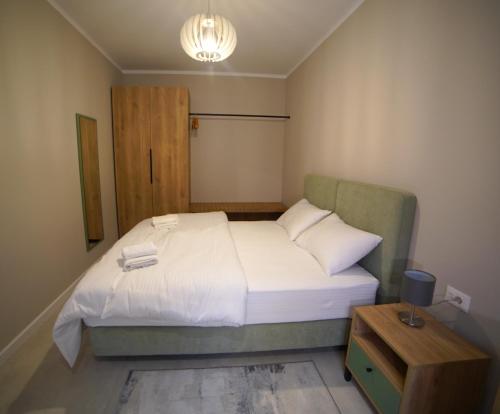 a bedroom with a white bed with a night stand at Center Oasis Appartmens in Tirana