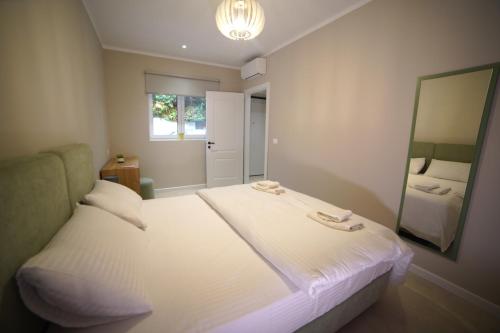 a bedroom with a large white bed and a mirror at Center Oasis Appartmens in Tirana