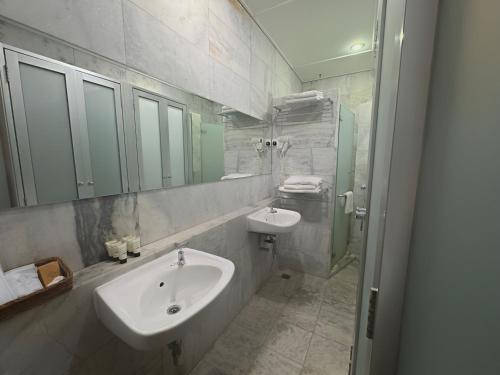 a white bathroom with a sink and a shower at Museum Hotel in George Town