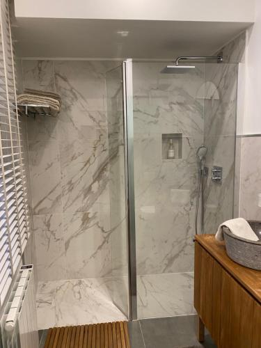 a shower with a glass door in a bathroom at Les Hortensias in Canly