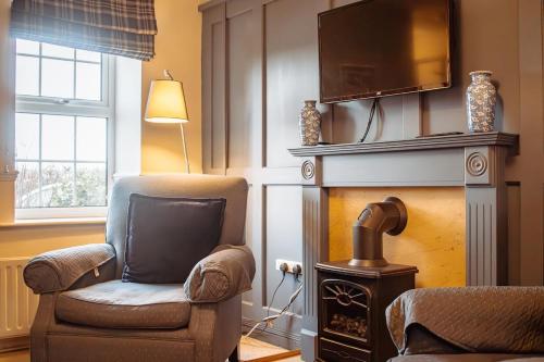 un soggiorno con una sedia e una televisione sopra un camino di Secret View Cottage, A Hidden Gem in Terrington a Terrington