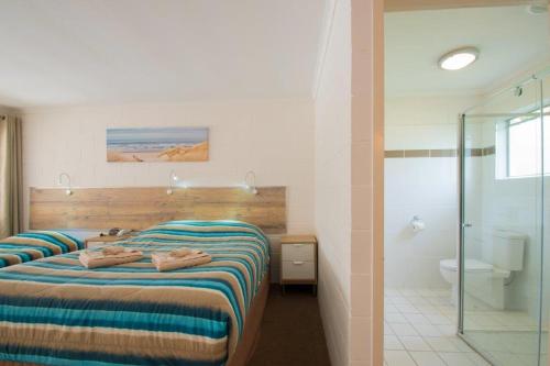 a hotel room with a bed and a bathroom at A & A Motel in Proserpine