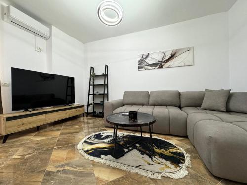 Una sala de estar con un sofá y un televisor de pantalla plana. en City Center Gem with Jacuzzi & Terrace, en Durrës
