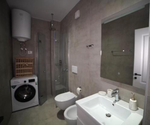 a bathroom with a sink and a toilet and a mirror at Center Oasis Appartmens in Tirana