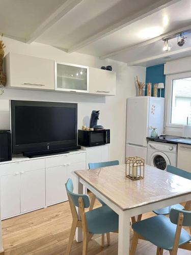 une cuisine avec une table avec des chaises et une télévision dans l'établissement La maison d'Oscar, 200m de la plage, à Asnelles