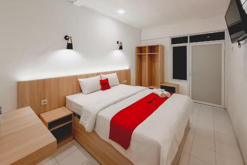 a bedroom with a large bed with a red blanket at RedDoorz at Grand Mirza Near Pasar Grosir Batik Setono Pekalongan in Pekalongan