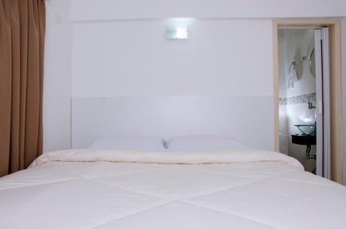 a white bed in a room with a window at Hotel Morada do Mar in Guarujá