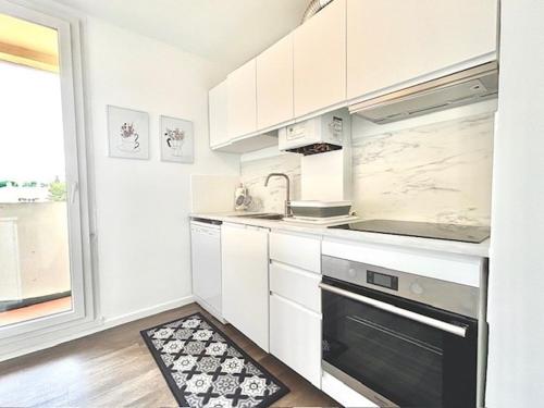 une cuisine avec des armoires blanches et un four à plaques de cuisson dans l'établissement Bel appartement lumineux Aix, à Aix-en-Provence