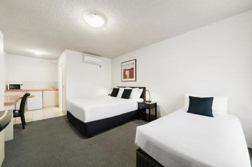 a hotel room with two beds and a desk at City Reach Motel in Wangaratta