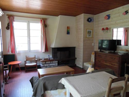 un salon avec une télévision, un canapé et une table dans l'établissement Villa de bord de mer, à La Tranche-sur-Mer