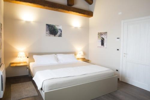 a white bedroom with a white bed and two lamps at Ca'Rapulin in Calosso