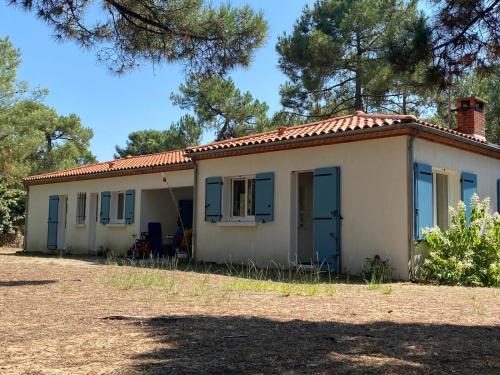 Une petite maison blanche avec volets bleus dans l'établissement Villa de bord de mer, à La Tranche-sur-Mer