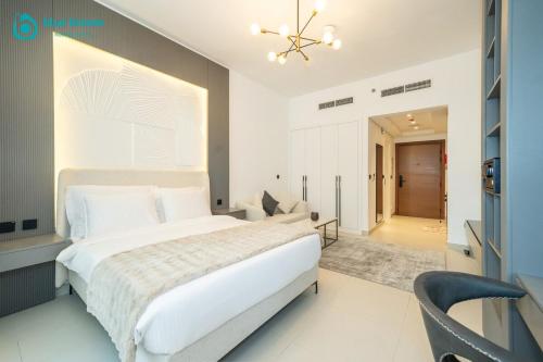 a bedroom with a large white bed and a chair at Blue Breeze - Trendy Studio with Balcony & Stylish Interiors in Dubai