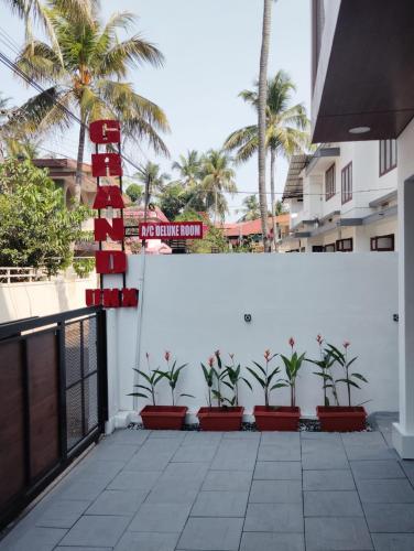 a white wall with palm trees and a street sign at Grand UNX in Kannur