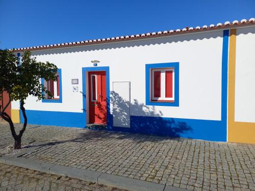 a blue and white house with a red door at Não te vou esquecer Aldeia da Luz! in Luz