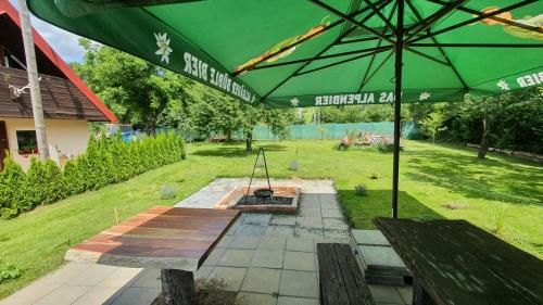a picnic table with a green umbrella in a field at Beskiden Prime Exclusiv Chalets in Prostřední Bečva