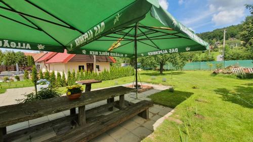 a picnic table with a green umbrella in a field at Beskiden Prime Exclusiv Chalets in Prostřední Bečva