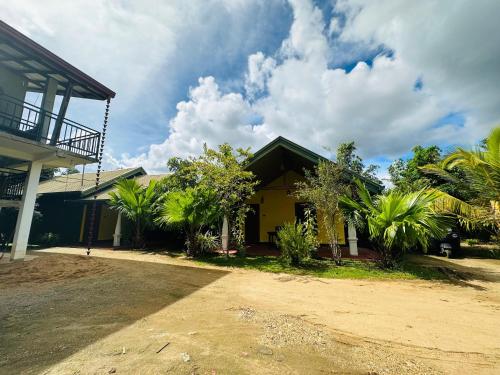 a yellow house with palm trees in front of it at Ceylon Safari Cottage in Udawalawe