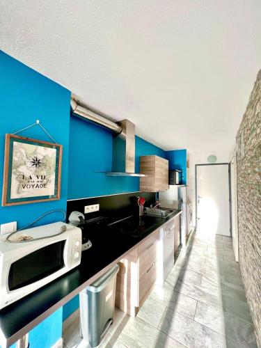 une cuisine avec des murs bleus et un comptoir noir dans l'établissement Studio le cosy, clim, Wi-Fi, terrasse, LGM parking, à La Grande Motte