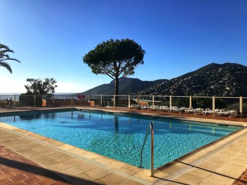 une piscine avec des chaises et une montagne en arrière-plan dans l'établissement Nautica - Appart 4 personnes vue mer, idéal famille, à Théoule-sur-Mer