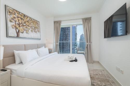 a white bedroom with a large bed and a window at Free housekeeping visits during your stay - StayShort - Marina Views and a 3 Bedroom Apartment in Dubai Marina in Dubai