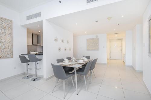 a white dining room with a table and chairs at Free housekeeping visits during your stay - StayShort - Marina Views and a 3 Bedroom Apartment in Dubai Marina in Dubai