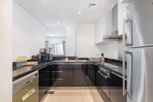 a kitchen with black cabinets and a stainless steel refrigerator at Free housekeeping visits during your stay - StayShort - Marina Views and a 3 Bedroom Apartment in Dubai Marina in Dubai