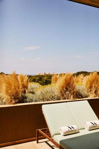 a bench sitting on a balcony looking out at the desert at Hôtel & Spa Version Maquis Citadelle in Bonifacio