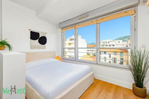une chambre avec un lit blanc et une grande fenêtre dans l'établissement Casa So Nice, à Nice
