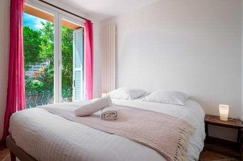 une chambre blanche avec un lit avec une fenêtre dans l'établissement Val de Menton, Charmant 3 pièces atypique, jardin et terrasse à 7 minutes à pied du centre ville, à Menton