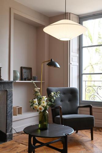 a living room with a chair and a table with flowers at Hôtel les Prés in Saint-Hilaire-le-Châtel