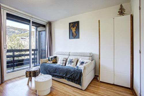 a living room with a couch and a large window at Le Petit Montagnard - Station accessible à pied in Les Angles
