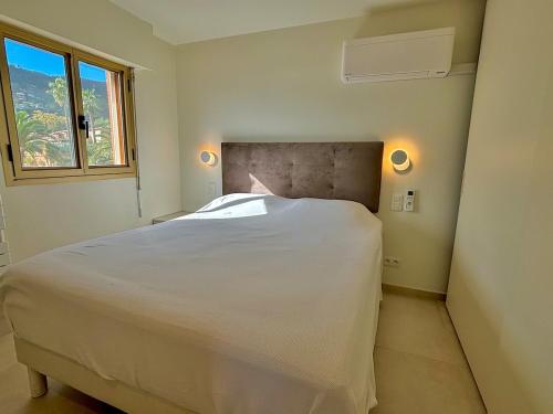 une chambre avec un lit blanc et une fenêtre dans l'établissement Appartement avec vue sur le port de la Figueirette, à Théoule-sur-Mer