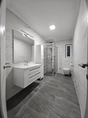 a white bathroom with a sink and a toilet at Villa Pauliana in Povljana