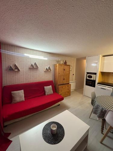 un salon avec un canapé rouge et une cuisine dans l'établissement Bel T2 in St Lary - Résidence Lustou, à Saint-Lary-Soulan