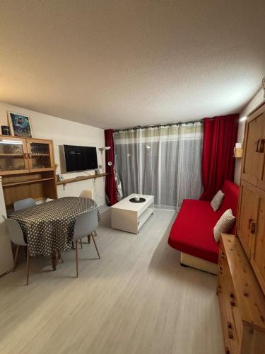 un salon avec une table et un canapé rouge dans l'établissement Bel T2 in St Lary - Résidence Lustou, à Saint-Lary-Soulan