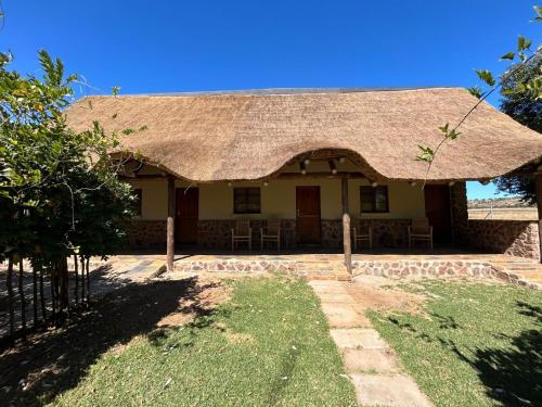 a house with a thatched roof and a yard at The Lions Foundation Rescue & Conservation Centre at Schrikkloof in Warmbaths